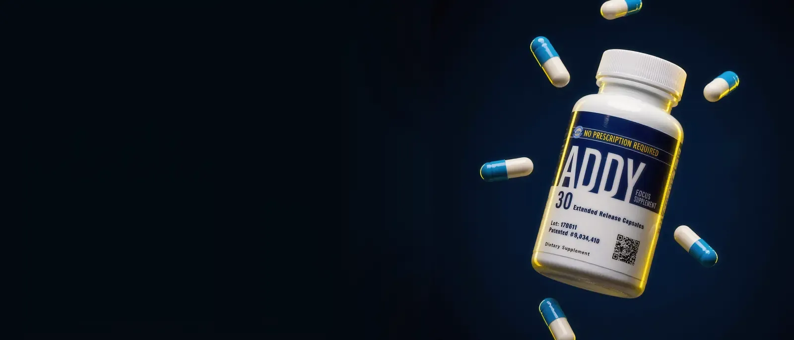 A bottle of ADDY 30 extended release capsules in mid-air on midnight navy, a yellow rim light along its edge, blue and white capsules floating around it.